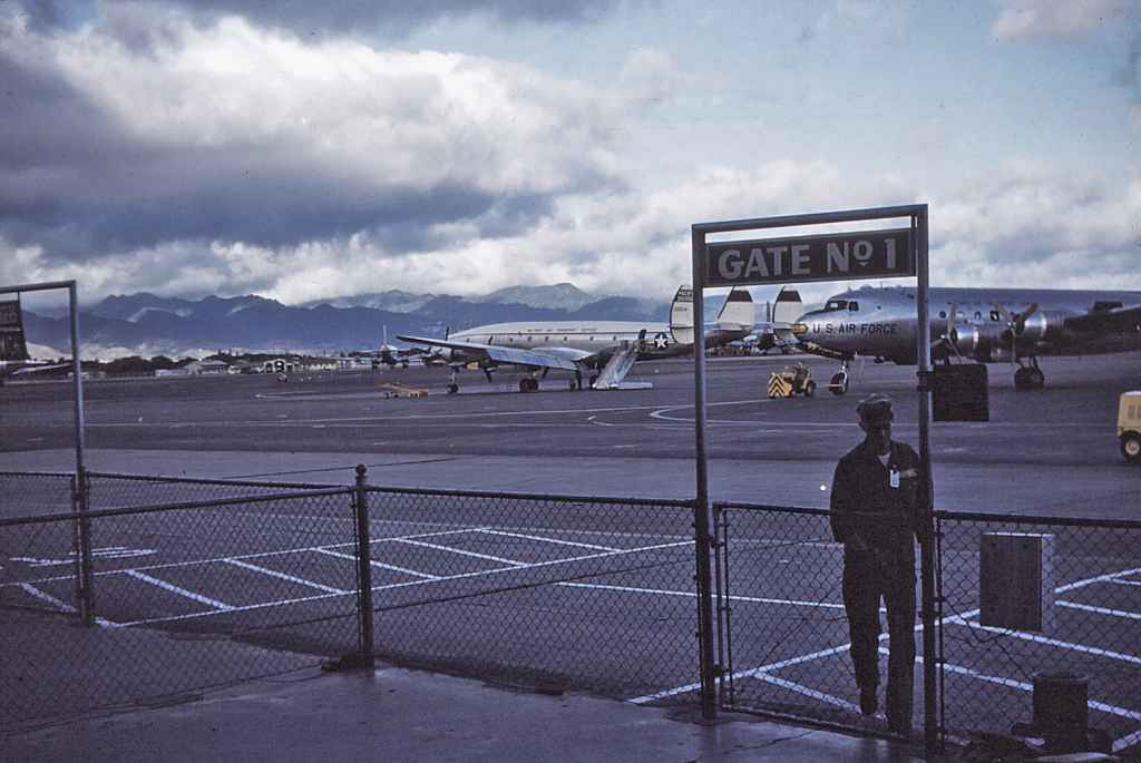 Hickam Air Force Base transient ramp Gate Number 1, with a MATS C-121 Connie and a C-54 resting between flights.  This images most likely dates from the early 1950s.