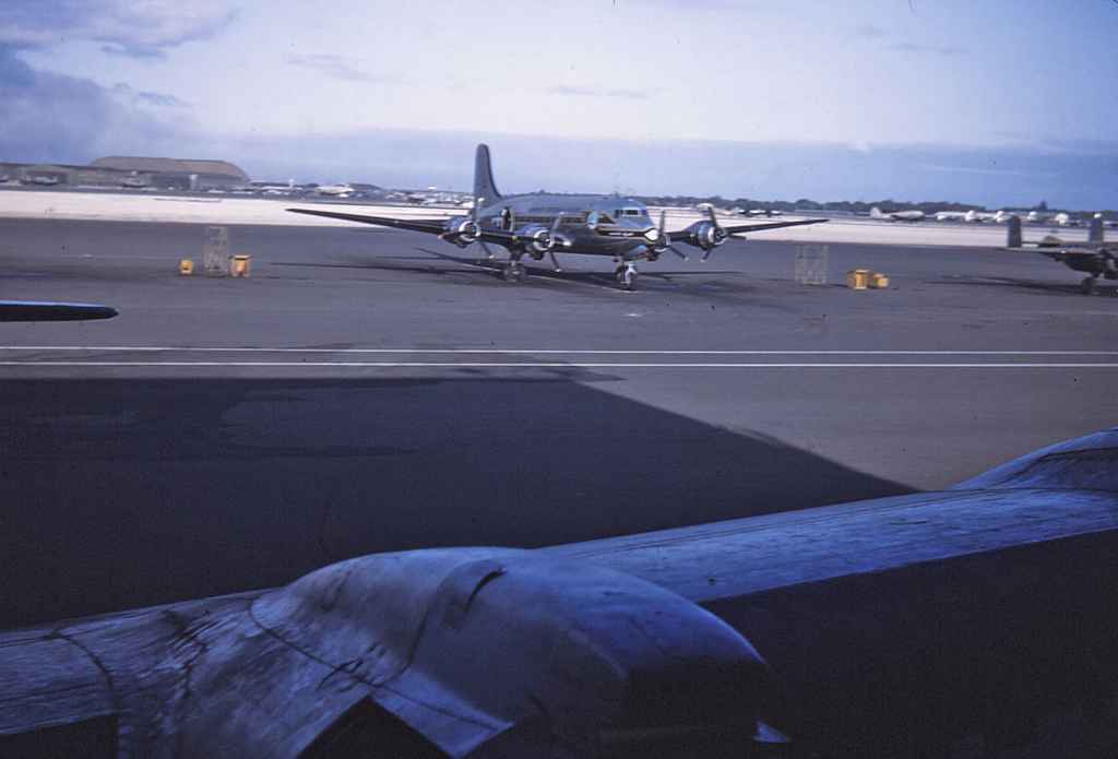A USAF MATS C-54 at rest on the Hickam apron, as viewed through the forward crew door on a sister C-54. Circa early 1950s.