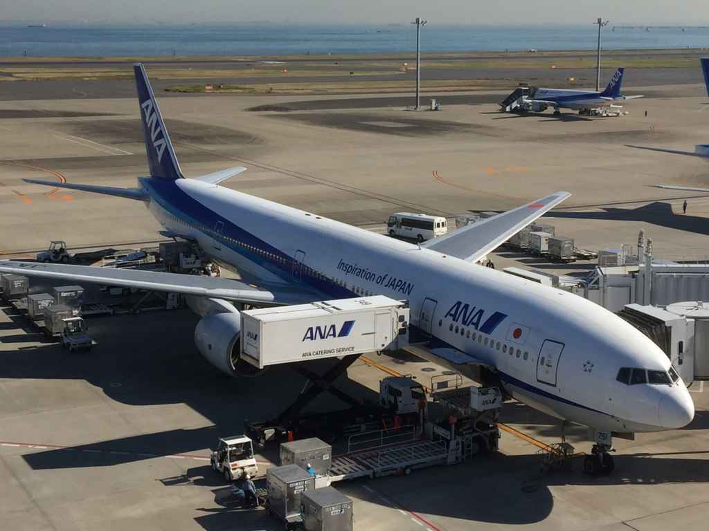 ANA 777 on the gate viewed from the obsdeck at Tokyo Haneda ANA Terminal 2 with Tokyo Bay in the background.