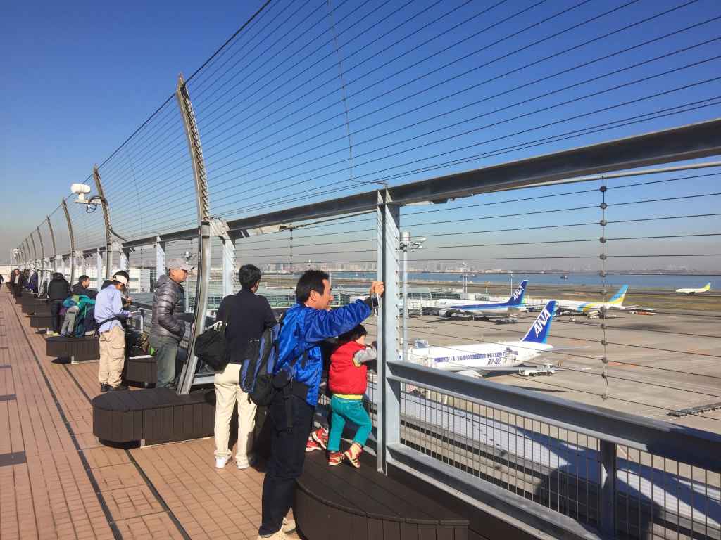 Punters enjoying the day on the obsdeck at Tokyo Haneda ANA Terminal 2 with Tokyo Bay in the background.