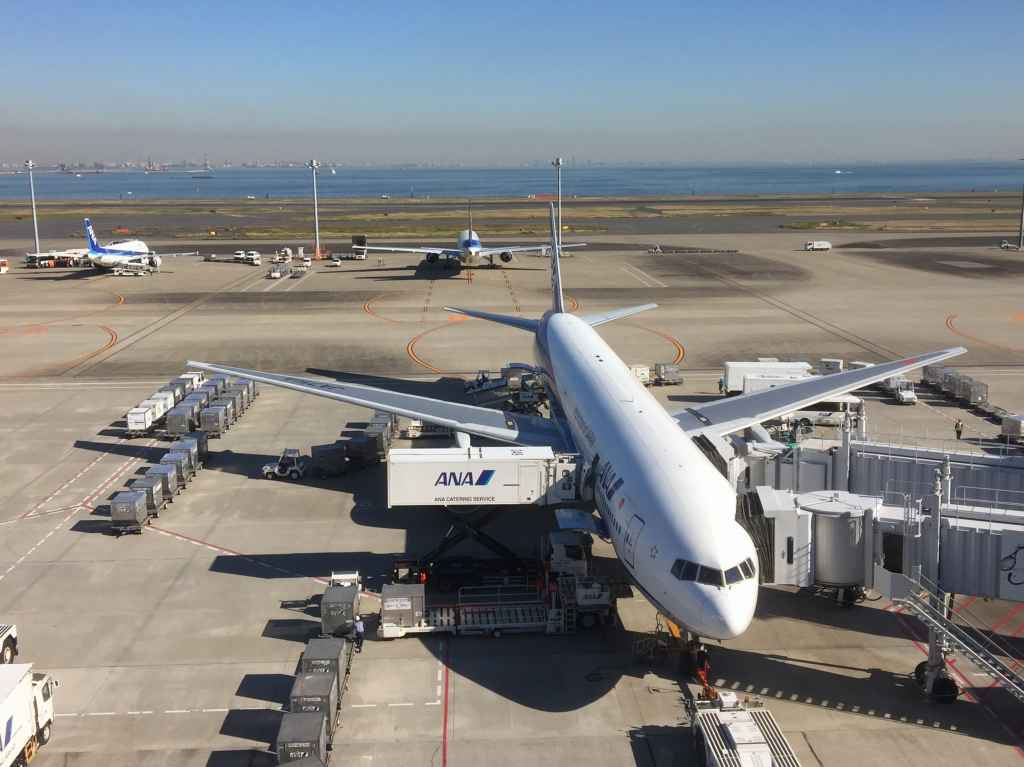 ANA triple seven being serviced at Tokyo Haneda ANA Terminal 2 with Tokyo Bay in the background.