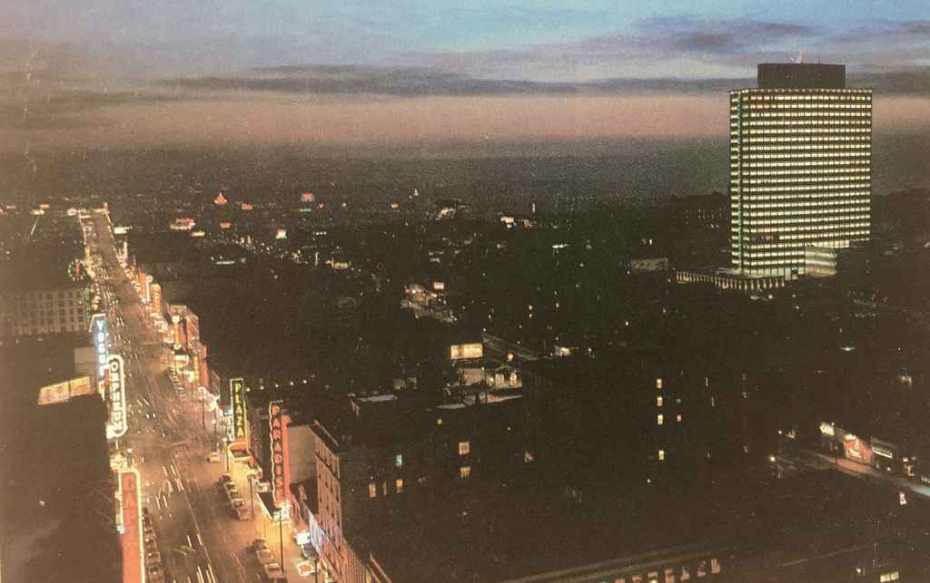 Dusk view of Granville Street looking south and the then new BC Electric Building circa mid 1950s. The BC Electric building was the new head office for the Vancouver based electric utility company in a modern 21 story, 285 foot high structure. (Rolly Ford photo, postcard published by Natural Color Productions LTD., Vancouver, B.C.)